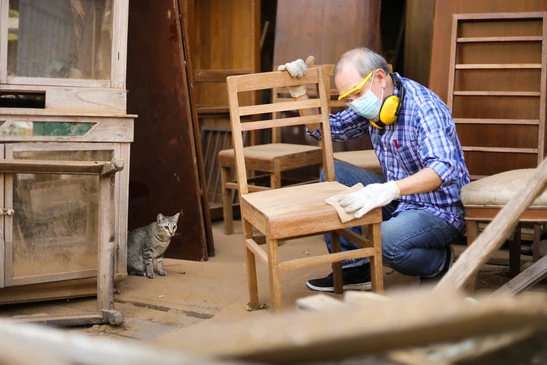 Atelier de menuiserie avec artisan senior restaurent une chaise en bois
