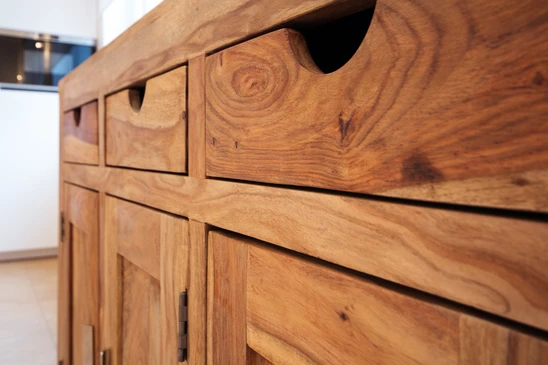 Meuble de cuisine en bois massif avec tiroirs et placards, présentant un veinage naturel apparent et finition artisanale