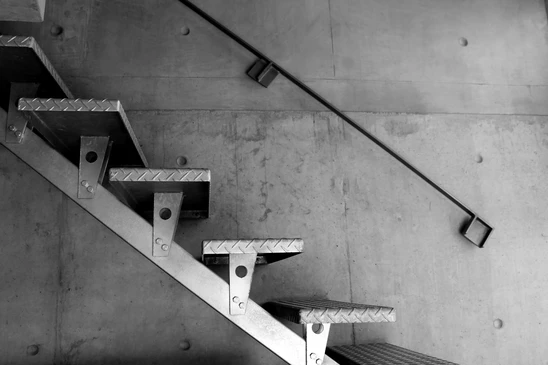 Escalier métallique industriel en acier avec marches antidérapantes à relief diamant, fixé sur mur en béton brut