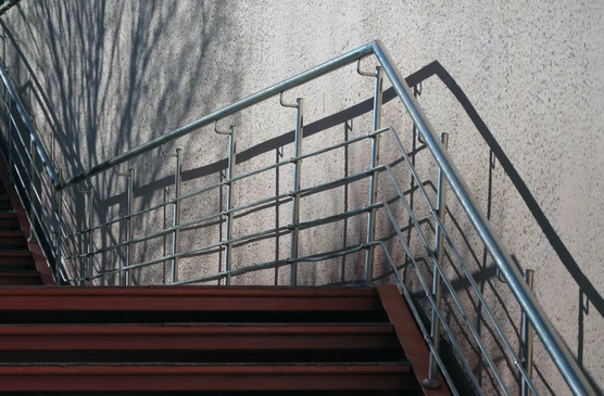 Escalier métallique industriel en acier avec marches antidérapantes à relief diamant, fixé sur mur en béton brut