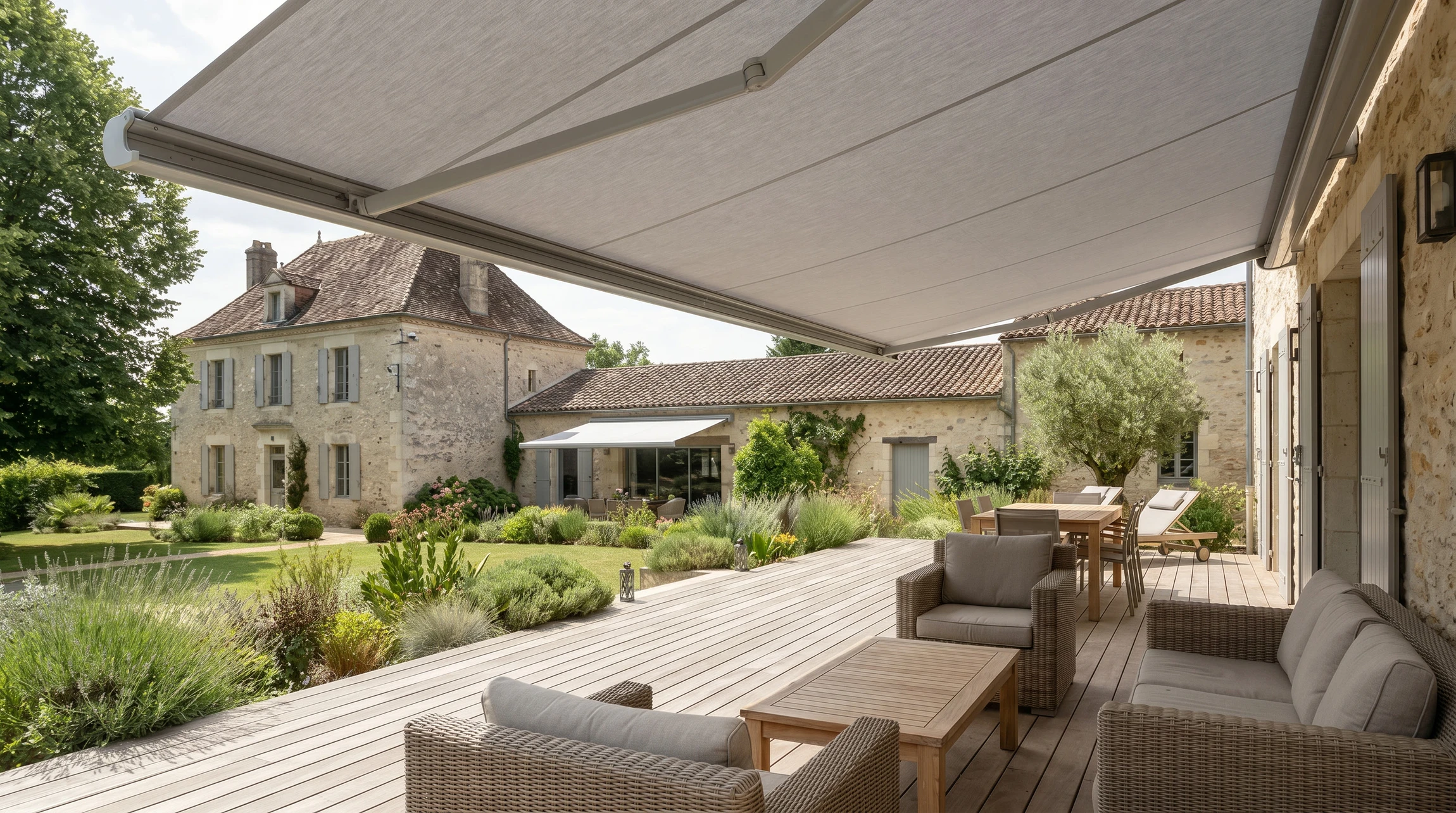 Terrasse résidentielle spacieuse avec un store extérieur gris ou blanc déroulable fixé au-dessus, offrant une ombre partielle à un mobilier de jardin confortable en dessous. La terrasse est construite en bois ou carrelage, avec une vue sur un jardin ou une maison. Le store est clairement visible, en bon état, et l'ensemble présente une ambiance accueillante et confortable propre à une installation de qualité professionnelle.
