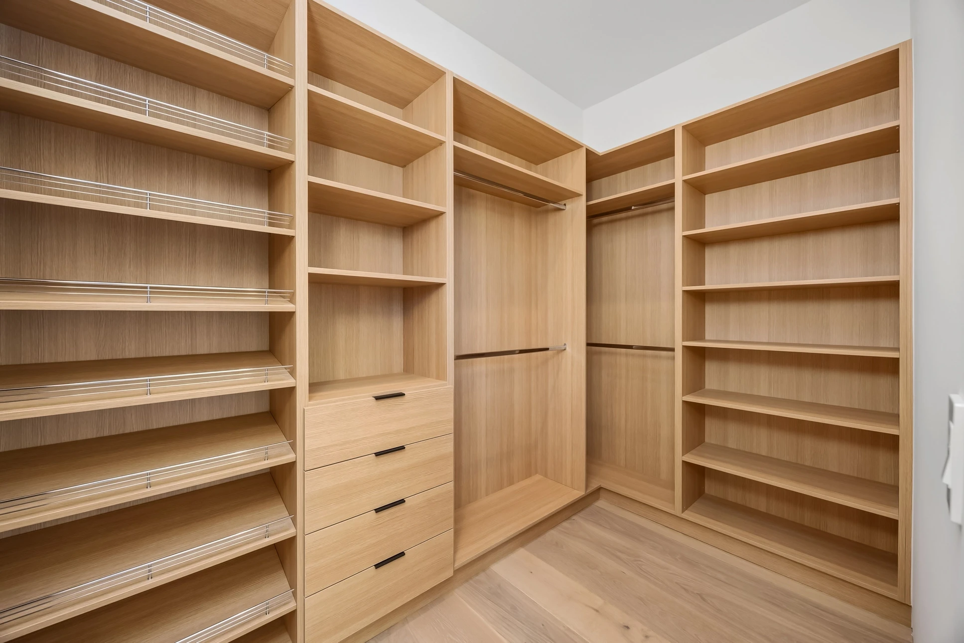 Chambre moderne avec dressing ouvert intégré au mur, présentant vêtements suspendus sur deux niveaux et chaussures rangées